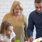 A family happily preparing vegetables together in a modern kitchen.