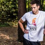 Man in forest wearing casual t-shirt, resting during outdoor workout.